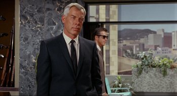 Movie still from “The Killers” (1964), directed by Don Siegel – A man in a suit and tie standing next to another man in a suit; Medium shot, Low angle