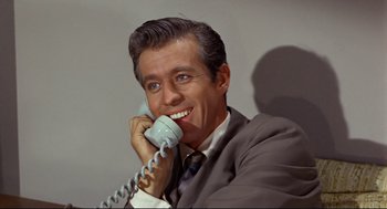 Movie still from “The Killers” (1964), directed by Don Siegel – A man in a suit and tie talking on a phone; Close Up shot, High angle