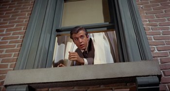 Movie still from “The Killers” (1964), directed by Don Siegel – A man looking out of an open window; Medium shot, Low angle