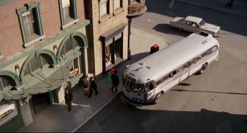 Movie still from “The Killers” (1964), directed by Don Siegel – People walking on the sidewalk next to a silver bus; Extreme Wide shot, High angle