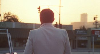 Movie still from “The Killing of a Chinese Bookie” (1976), directed by John Cassavetes – A man in a white jacket is looking at the sunset; Medium shot, Over the shoulder angle