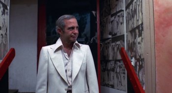 Movie still from “The Killing of a Chinese Bookie” (1976), directed by John Cassavetes – An older man in a white suit standing in front of a wall; Medium shot, Low angle
