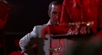 Movie still from “The Killing of a Chinese Bookie” (1976), directed by John Cassavetes – A man sitting at a table with a glass of wine; Medium shot, Over the shoulder angle