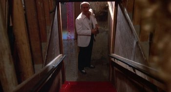 Movie still from “The Killing of a Chinese Bookie” (1976), directed by John Cassavetes – A man in a white jacket standing in an open doorway; Wide shot, Low angle