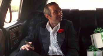 Movie still from “The Killing of a Chinese Bookie” (1976), directed by John Cassavetes – A man sitting in a chair smoking a cigarette; Medium shot, Low angle