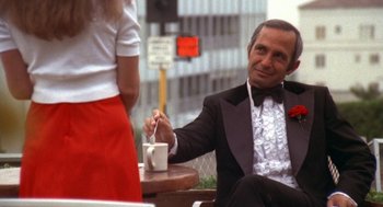 Movie still from “The Killing of a Chinese Bookie” (1976), directed by John Cassavetes – A man in a tuxedo sitting at a table with a cup of coffee; Medium shot, Low angle