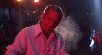 Movie still from “The Killing of a Chinese Bookie” (1976), directed by John Cassavetes – A man in a white dress shirt is smoking a cigarette; Close Up shot, Low angle
