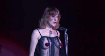 Movie still from “The Killing of a Chinese Bookie” (1976), directed by John Cassavetes – A woman in a see - through dress holding a microphone; Medium shot, Low angle