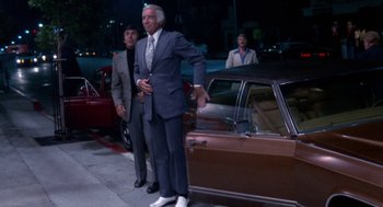 Movie still from “The Killing of a Chinese Bookie” (1976), directed by John Cassavetes – A man standing next to a car on the side of the street; Wide shot, Low angle