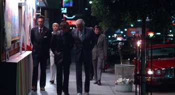 Movie still from “The Killing of a Chinese Bookie” (1976), directed by John Cassavetes – A group of people walking down a sidewalk at night; Wide shot, Low angle