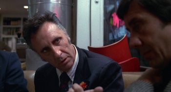 Movie still from “The Killing of a Chinese Bookie” (1976), directed by John Cassavetes – A man in a suit and tie sitting next to another man; Close Up shot, Over the shoulder angle