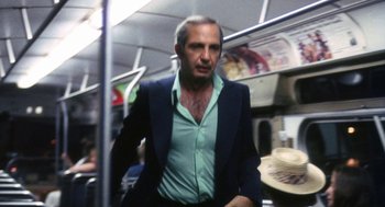 Movie still from “The Killing of a Chinese Bookie” (1976), directed by John Cassavetes – A man in a suit and tie riding a bus; Medium shot, Low angle