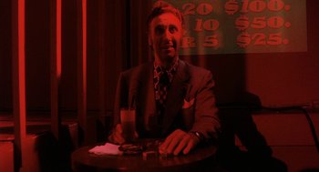 Movie still from “The Killing of a Chinese Bookie” (1976), directed by John Cassavetes – A man sitting at a table with a drink in front of him; Medium shot, Low angle