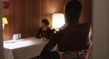 Movie still from “The Killing of a Chinese Bookie” (1976), directed by John Cassavetes – Two people sitting at a table in front of a lamp; Medium shot, Over the shoulder angle