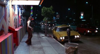 Movie still from “The Killing of a Chinese Bookie” (1976), directed by John Cassavetes – A woman walking down the sidewalk next to a yellow taxi cab; Wide shot, Low angle