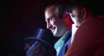 Movie still from “The Killing of a Chinese Bookie” (1976), directed by John Cassavetes – A man is speaking into a microphone at an event; Close Up shot, Low angle