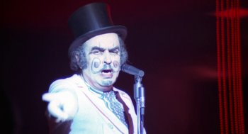 Movie still from “The Killing of a Chinese Bookie” (1976), directed by John Cassavetes – A man in a top hat and a microphone; Close Up shot, High angle