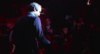 Movie still from “The Killing of a Chinese Bookie” (1976), directed by John Cassavetes – A group of people sitting in a dark room; Medium shot, Over the shoulder angle