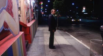 Movie still from “The Killing of a Chinese Bookie” (1976), directed by John Cassavetes – A man standing on the side of the street at night; Wide shot, High angle