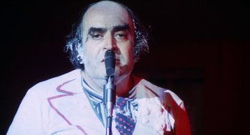 Movie still from “The Killing of a Chinese Bookie” (1976), directed by John Cassavetes – A man in a white jacket is holding a microphone; Close Up shot, High angle