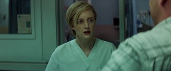 Movie still from “The Kindness of Strangers” (2019), directed by Lone Scherfig – A woman in a white lab coat looking into a mirror; Close Up shot, Over the shoulder angle