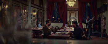 Movie still from “The Kindness of Strangers” (2019), directed by Lone Scherfig – Two men are sitting at a table in a restaurant; Wide shot, Over the shoulder angle