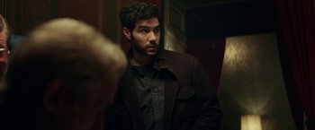 Movie still from “The Kindness of Strangers” (2019), directed by Lone Scherfig – A man wearing a brown jacket looking at the camera; Medium shot, Over the shoulder angle