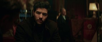 Movie still from “The Kindness of Strangers” (2019), directed by Lone Scherfig – A person wearing a suit and tie; Close Up shot, Over the shoulder angle