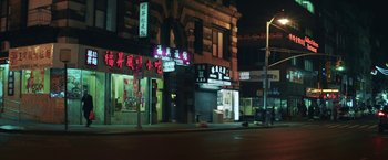 Movie still from “The Kindness of Strangers” (2019), directed by Lone Scherfig – A city street at night lit up by neon lights; Extreme Wide shot, High angle