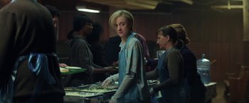 Movie still from “The Kindness of Strangers” (2019), directed by Lone Scherfig – A group of people standing around a table; Medium shot, Over the shoulder angle