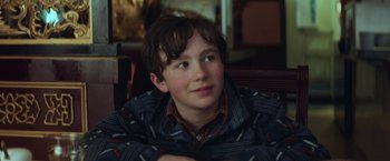 Movie still from “The Kindness of Strangers” (2019), directed by Lone Scherfig – A young boy sitting in front of a wooden table; Close Up shot, Over the shoulder angle