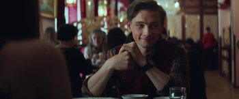 Movie still from “The Kindness of Strangers” (2019), directed by Lone Scherfig – A man sitting at a table in front of other people; Close Up shot, Over the shoulder angle