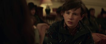 Movie still from “The Kindness of Strangers” (2019), directed by Lone Scherfig – A young boy sitting on a chair in a room; Close Up shot, Over the shoulder angle