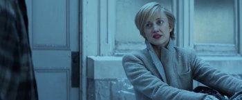 Movie still from “The Kindness of Strangers” (2019), directed by Lone Scherfig – A woman wearing a gray coat standing in front of a building; Close Up shot, Over the shoulder angle