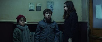 Movie still from “The Kindness of Strangers” (2019), directed by Lone Scherfig – A young boy and a young woman standing next to each other; Medium shot, High angle