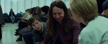 Movie still from “The Kindness of Strangers” (2019), directed by Lone Scherfig – A woman and a boy crying in a crowded room; Close Up shot, Over the shoulder angle