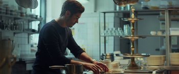 Movie still from “The Kindness of Strangers” (2019), directed by Lone Scherfig – A man in a kitchen preparing food on a counter; Medium shot, Low angle