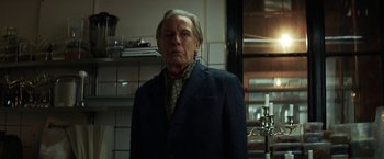 Movie still from “The Kindness of Strangers” (2019), directed by Lone Scherfig – An older man standing in a dark kitchen; Medium shot, Low angle
