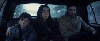 Movie still from “The Kindness of Strangers” (2019), directed by Lone Scherfig – A woman sitting in the back of a car with two other people; Medium shot, High angle