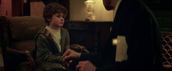 Movie still from “The Kindness of Strangers” (2019), directed by Lone Scherfig – A young boy sitting in front of an older gentleman; Medium shot, Over the shoulder angle