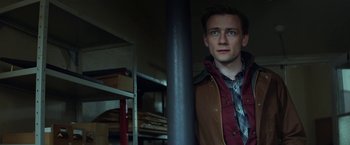 Movie still from “The Kindness of Strangers” (2019), directed by Lone Scherfig – A man standing next to a pole in a room; Medium shot, Low angle