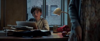 Movie still from “The Kindness of Strangers” (2019), directed by Lone Scherfig – A young boy sitting at a table with a laptop computer in front of him; Medium shot, Over the shoulder angle