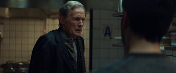 Movie still from “The Kindness of Strangers” (2019), directed by Lone Scherfig – An older man wearing a jacket and a tie; Medium shot, Over the shoulder angle