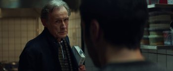 Movie still from “The Kindness of Strangers” (2019), directed by Lone Scherfig – An older man holding a book in front of a mirror; Close Up shot, Over the shoulder angle