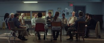 Movie still from “The Kindness of Strangers” (2019), directed by Lone Scherfig – A group of people sitting in a circle talking to each other; Wide shot, High angle