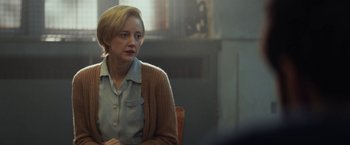 Movie still from “The Kindness of Strangers” (2019), directed by Lone Scherfig – A woman sitting at a table in a room; Medium shot, Over the shoulder angle