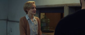 Movie still from “The Kindness of Strangers” (2019), directed by Lone Scherfig – A woman standing in front of a fire place; Medium shot, Over the shoulder angle