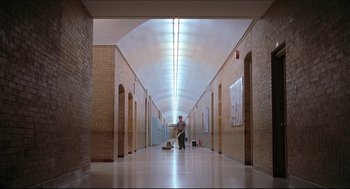 Movie still from “Good Will Hunting” (1997), directed by Gus Van Sant – A man standing in an empty hallway with lights overhead; Wide shot, Low angle