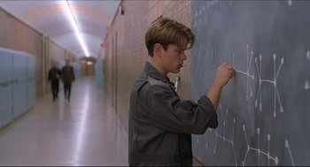 Movie still from “Good Will Hunting” (1997), directed by Gus Van Sant – A man writing on a chalkboard in a school hallway; Medium shot, Over the shoulder angle