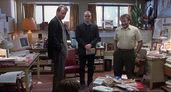 Movie still from “Good Will Hunting” (1997), directed by Gus Van Sant – A group of men standing in front of a pile of books in a room; Wide shot, Over the shoulder angle